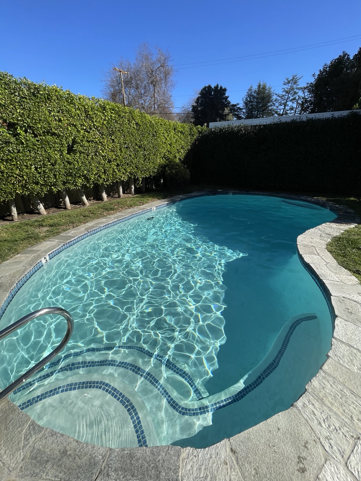 Sunlit residential swimming pool with clean sparkling blue water