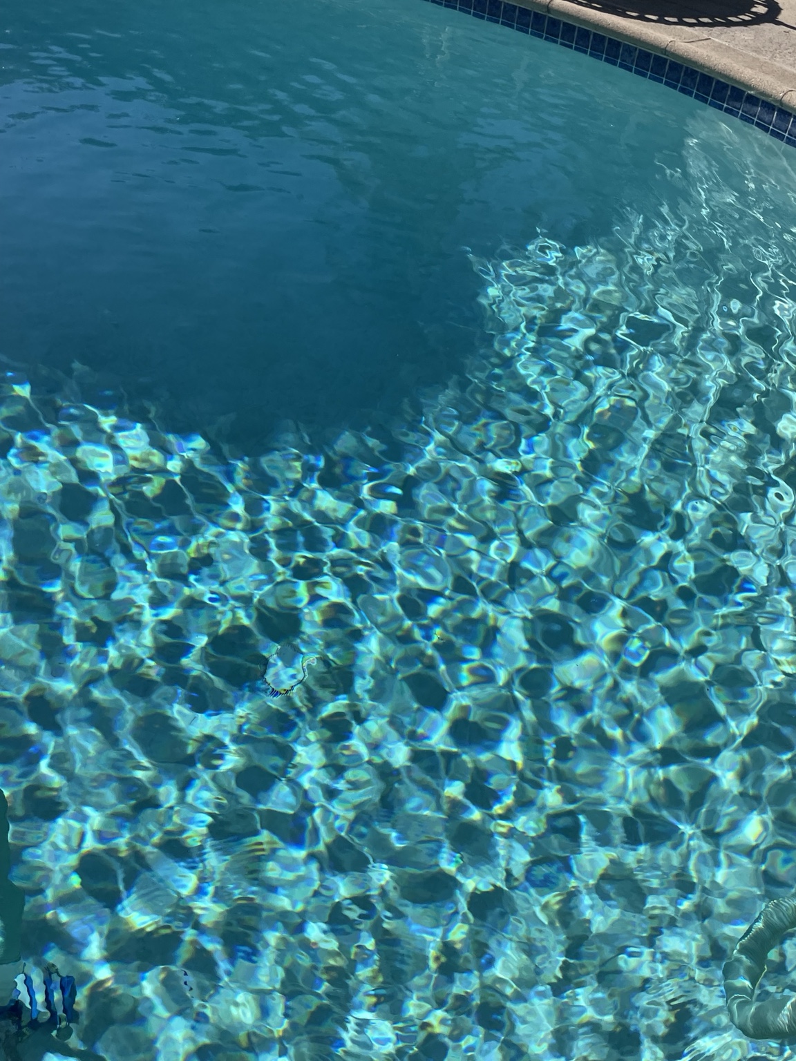 Close-up of clear pool water with visible blue sunlight reflections